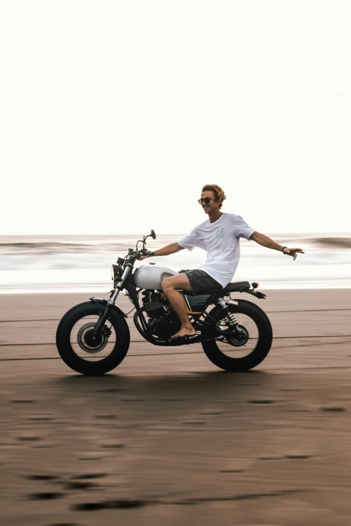 Young man enjoying a carefree motorcycle ride on a Bali beach, showcasing leisure and adventure.